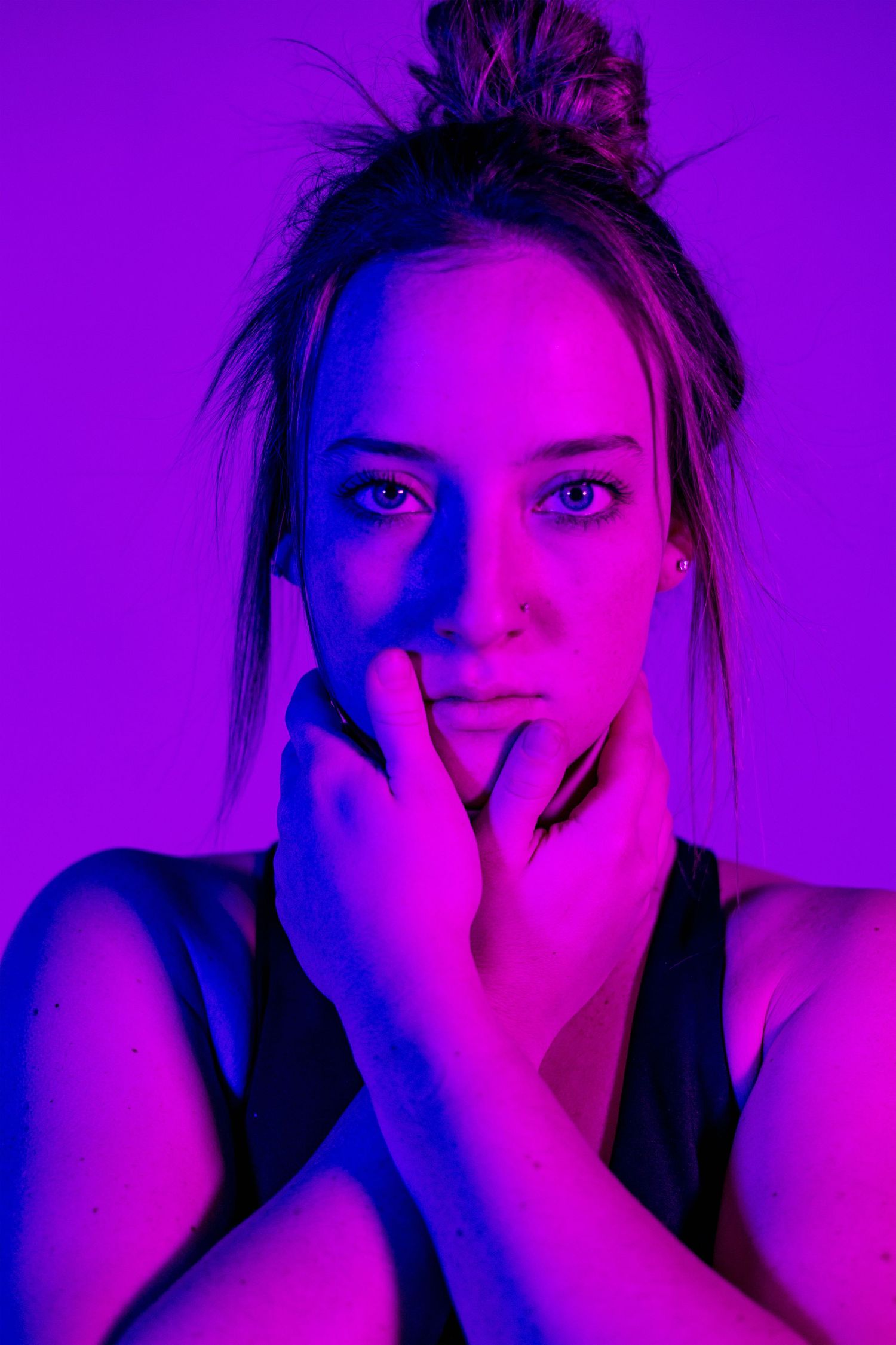 Close-up portrait with dramatic purple neon lighting creating an artistic moody atmosphere.