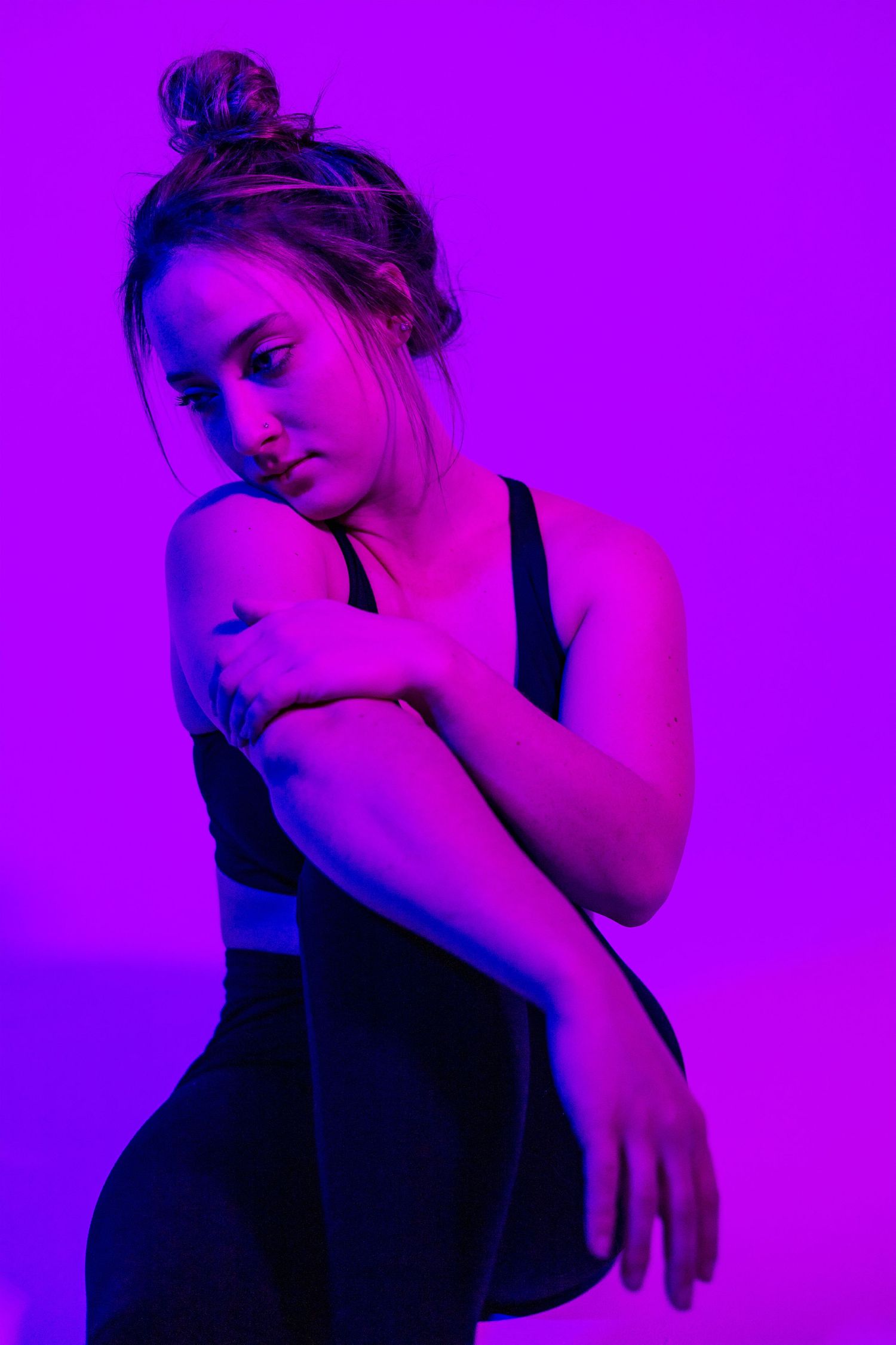 Person in black tank top against purple background in artistic lighting series.