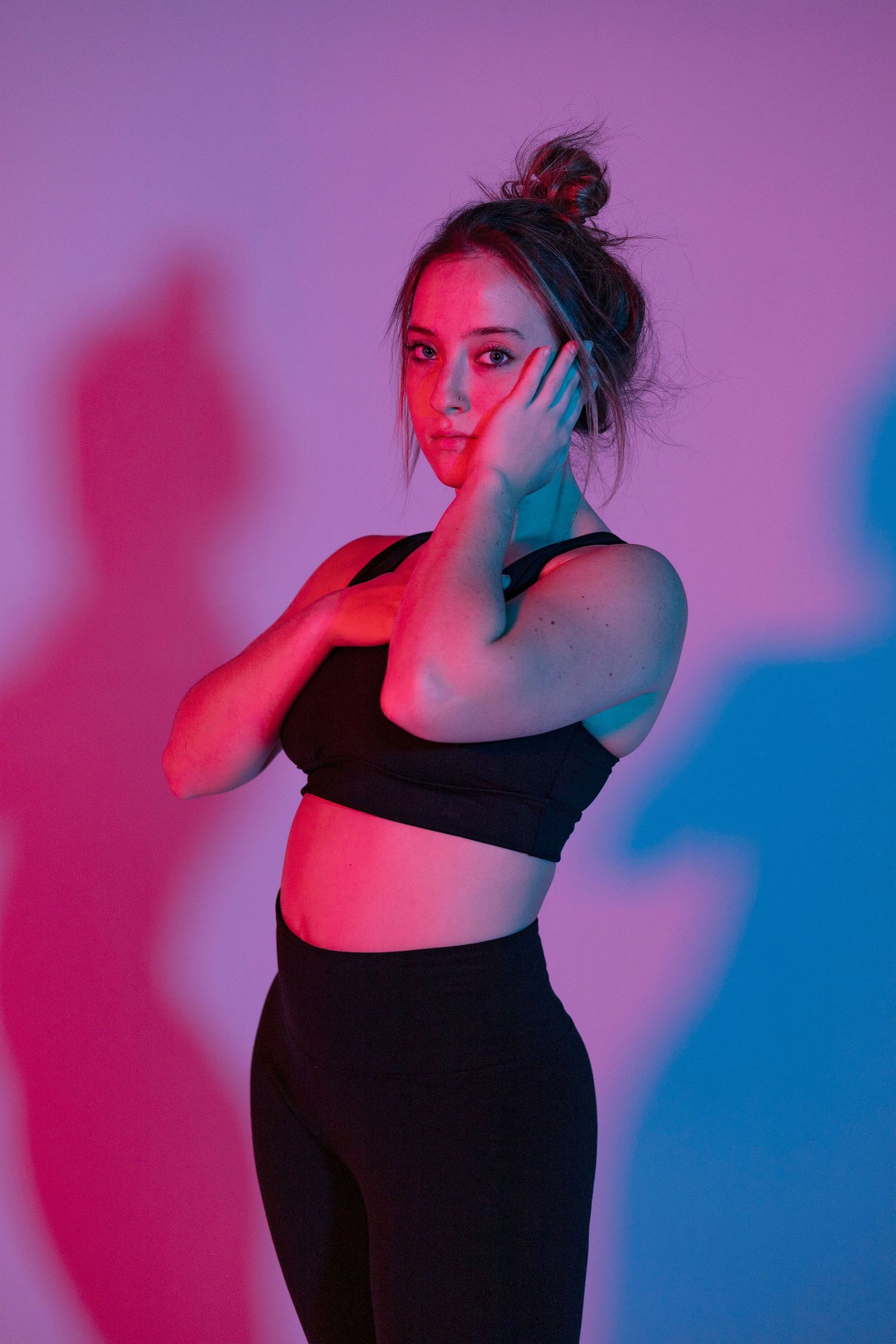 Figure in black against pink and blue gradient lighting creating dramatic shadows.