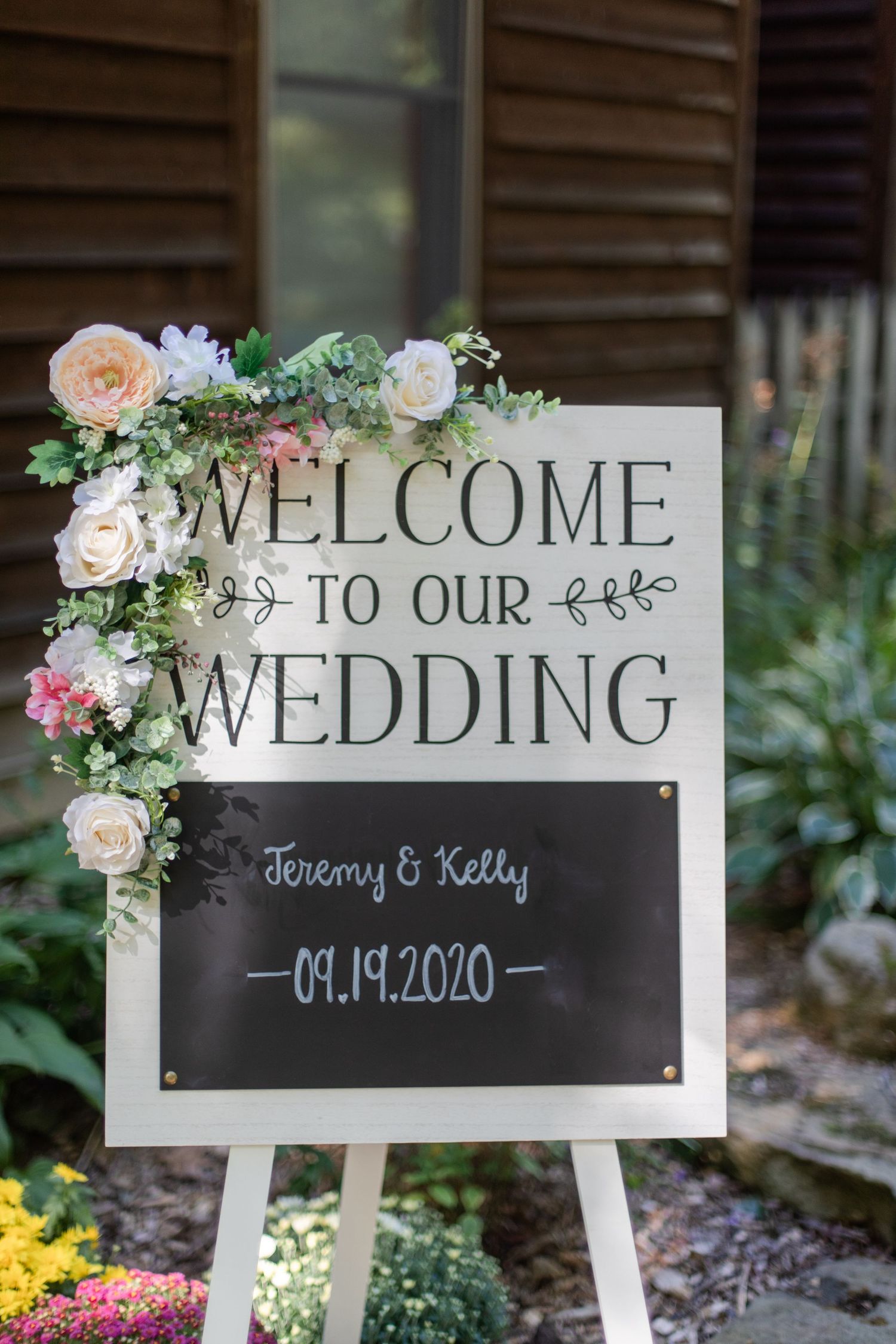 Rustic wedding welcome signs decorated with pink roses and greenery displayed in white frames.