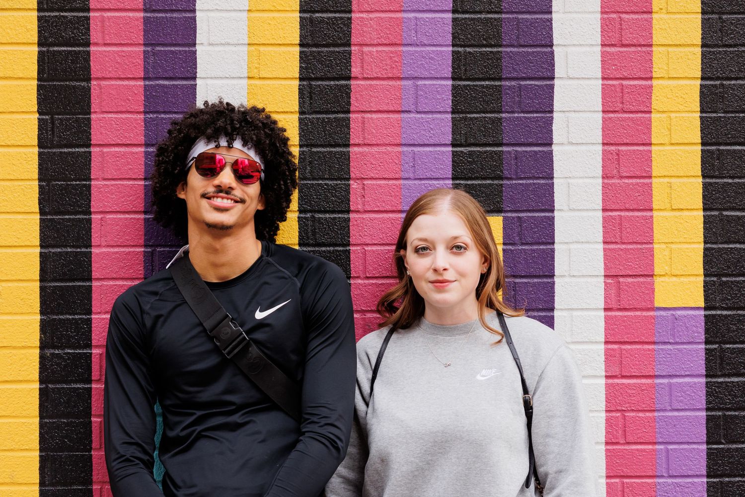 Candid group photo in front of a vibrant striped wall featuring bold yellow and pink stripes.