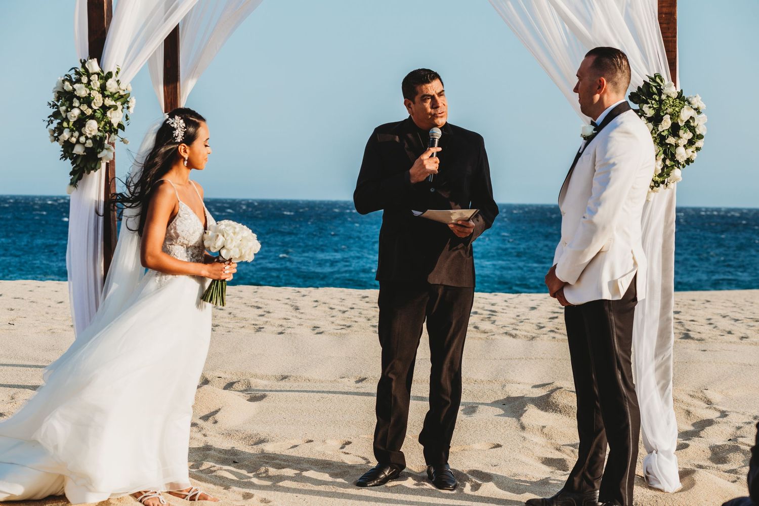 Bride and groom standing at the alter on the beach in Cabo Mexico as they get married.