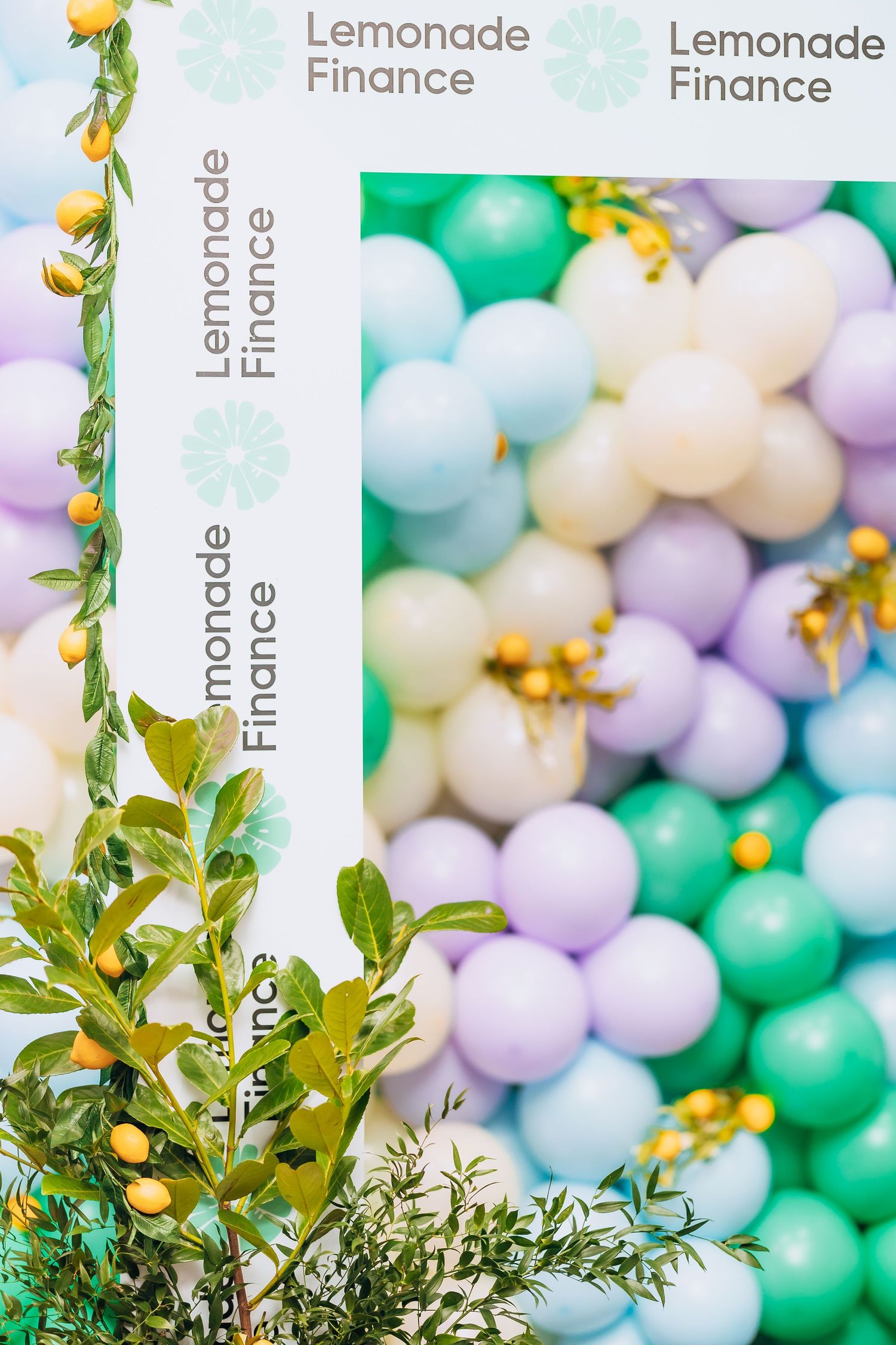 Decorative balloon wall in pastel colors with Lemonade Finance branding and greenery.