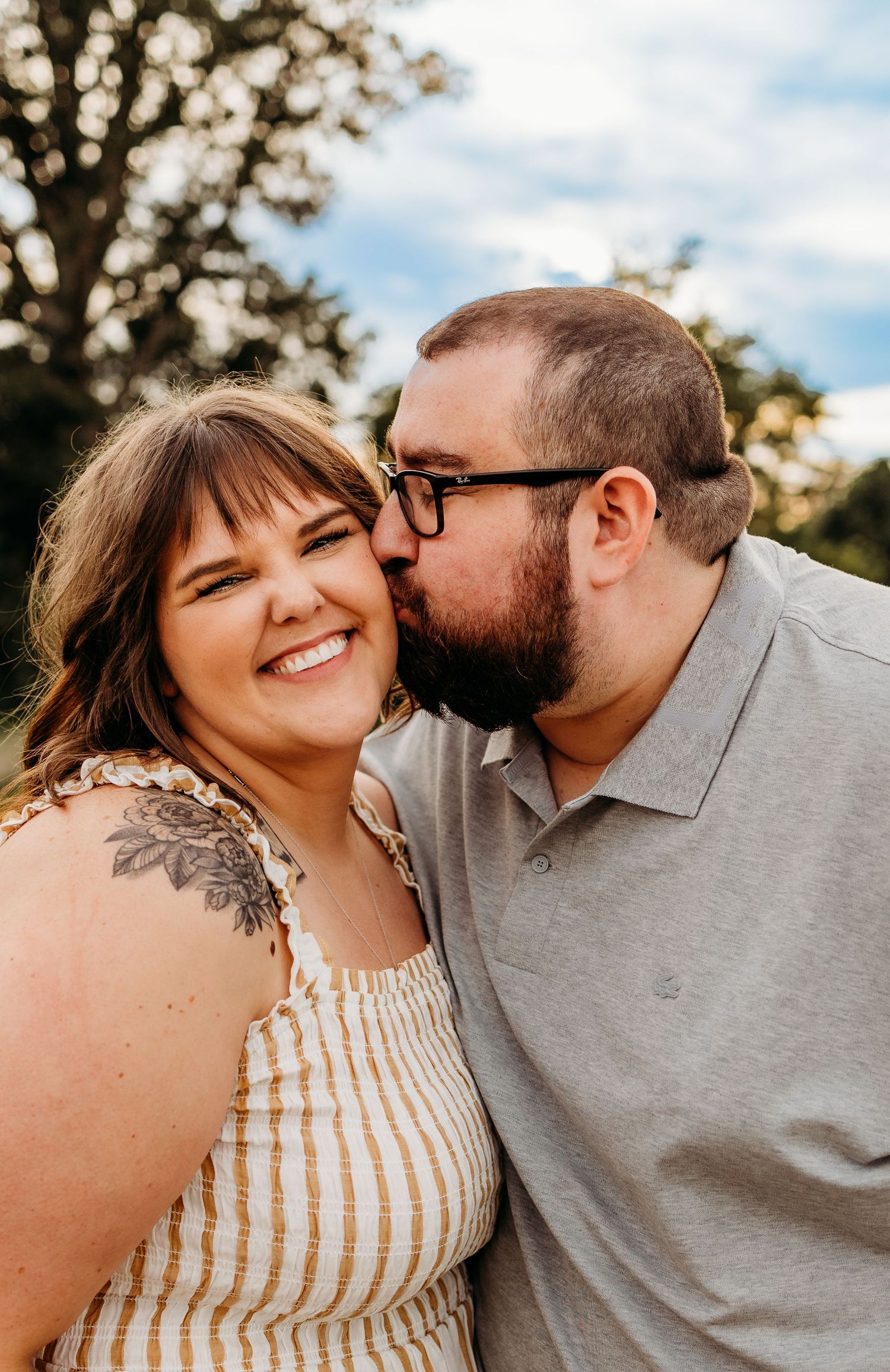 Young couple kissing on the cheek during engagement session