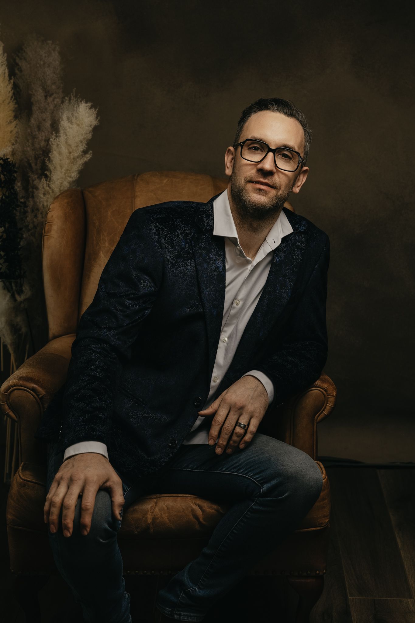 Artistic studio portraits with dramatic lighting and brown leather chair setting.