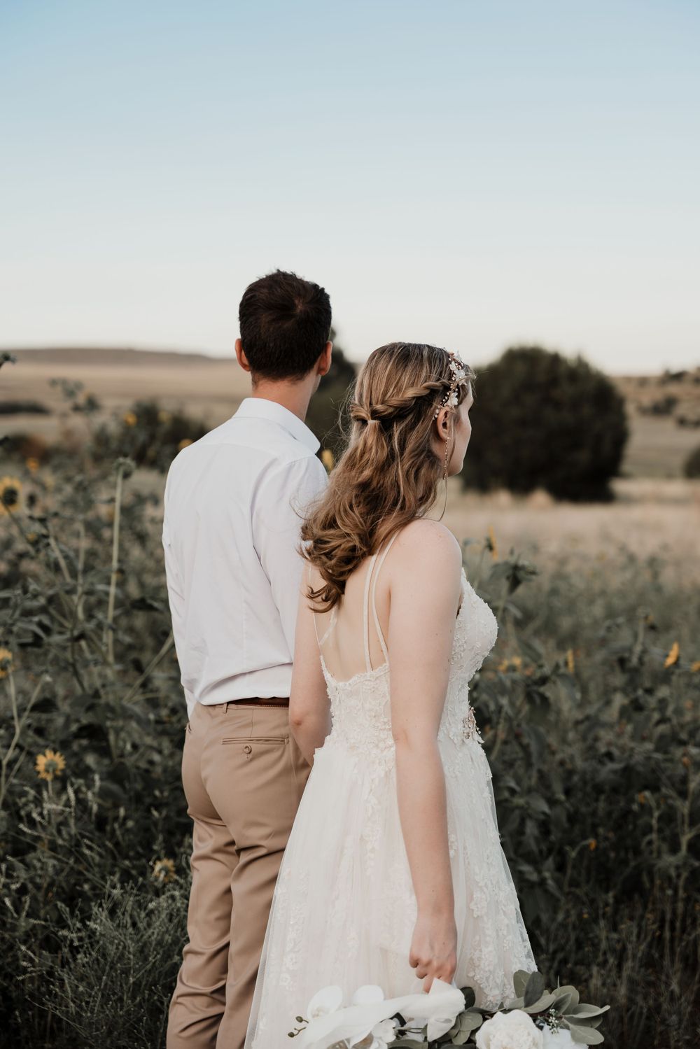 Couple stands together overlooking scenic desert landscape at dusk.