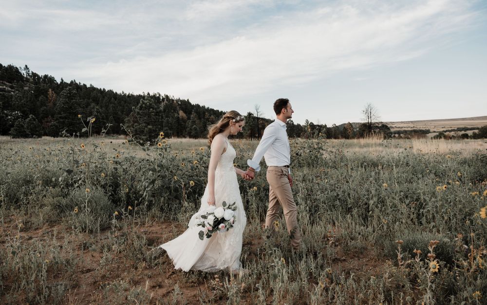 Joyful dancing moment between couple in mountain meadow with wildflowers.