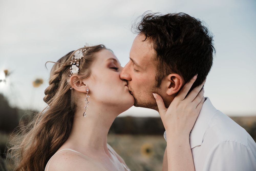 Passionate kiss captured between newlyweds in golden evening light.