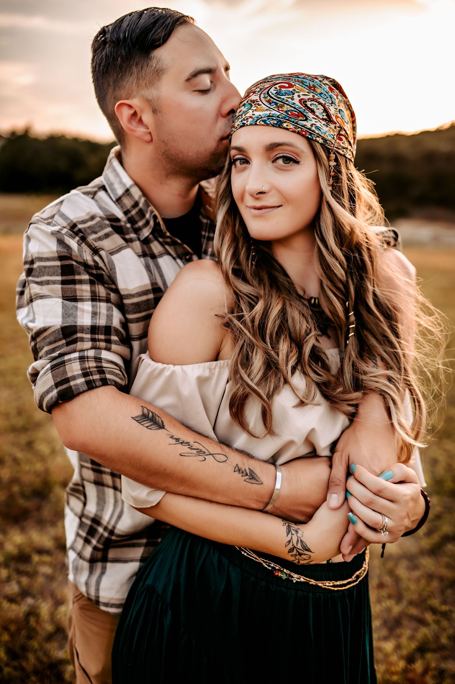 Romantic couple embracing in sunset field with rustic autumn styling.