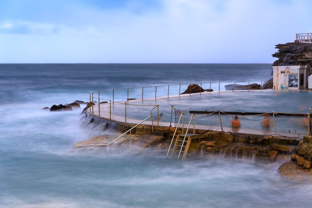 Landscape photo of an ocean baths with waves swirling around it