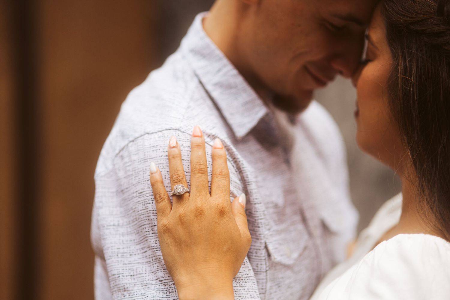 Close-up of engagement ring as couple shares intimate moment.