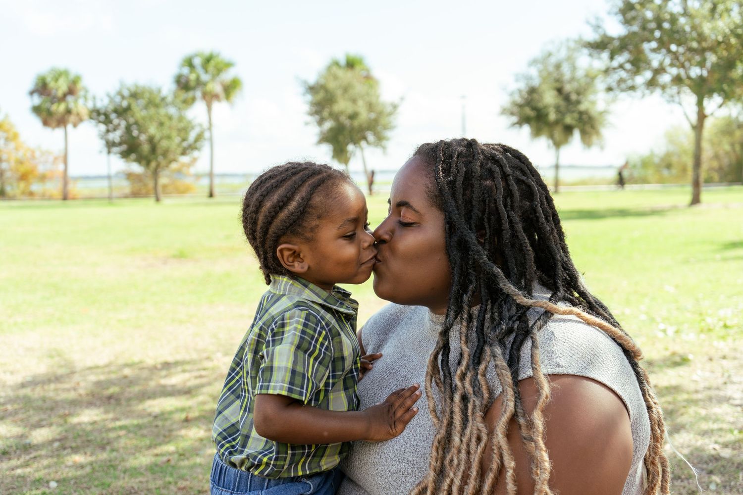 Mother kissing her 1 year old son at the park