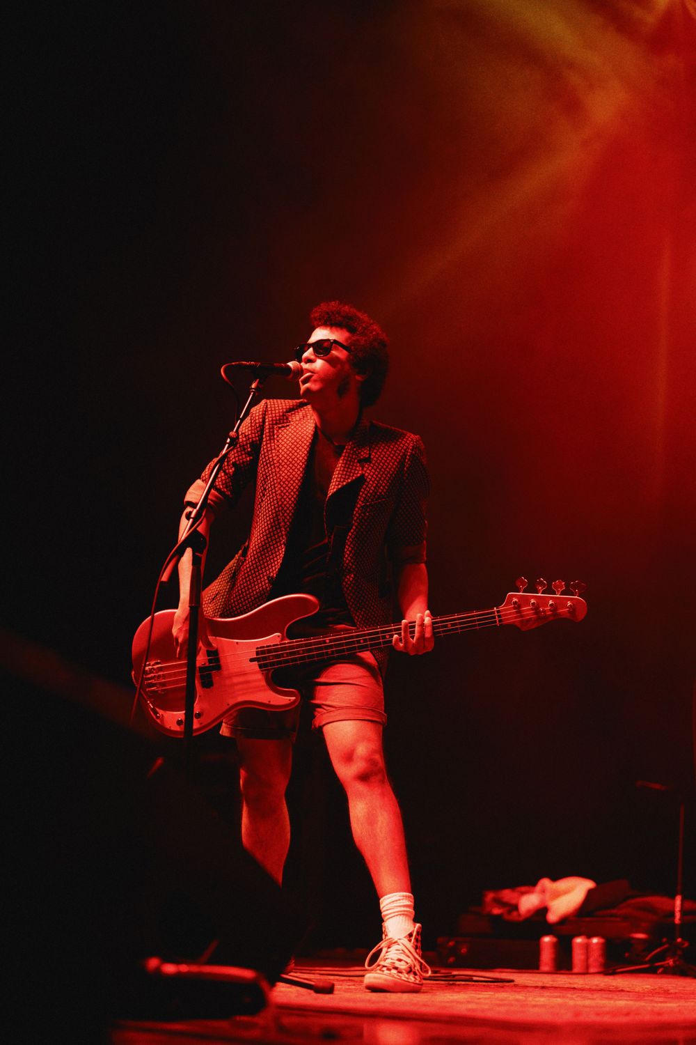 Bass player performing on stage bathed in dramatic red lighting effects.