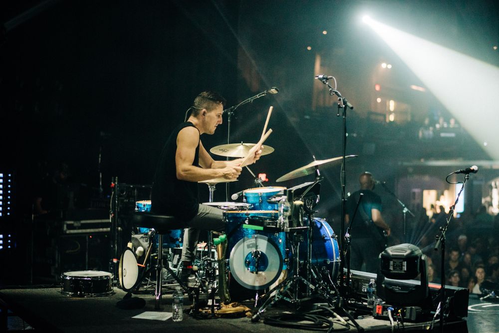 Dramatic concert stage setup with bright white spotlight and musical equipment in silhouette.