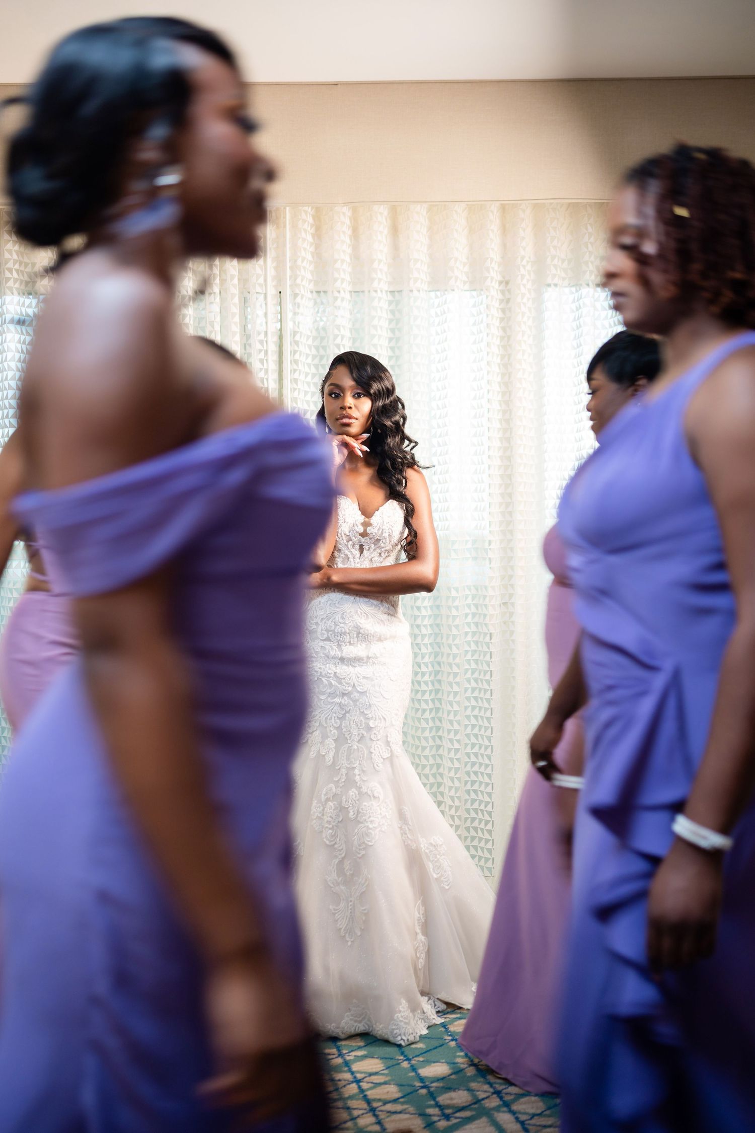Bridesmaids in purple dresses gather around bride in elegant white gown.