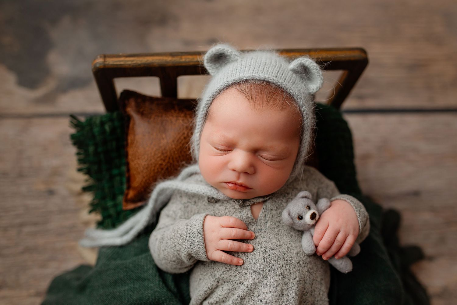 Baby boy sleeping in grey bear hat with teddy bear on small wooden bead in Flowertown Photography Studio in Summerville, SC