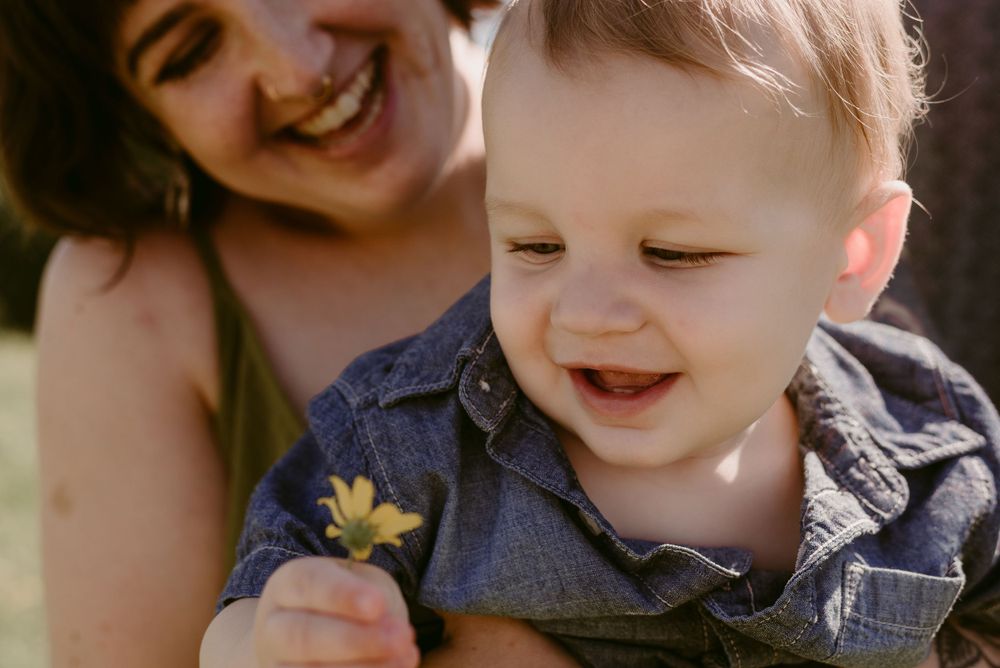 A joyful moment shared while holding a small yellow flower in a sunny field.
