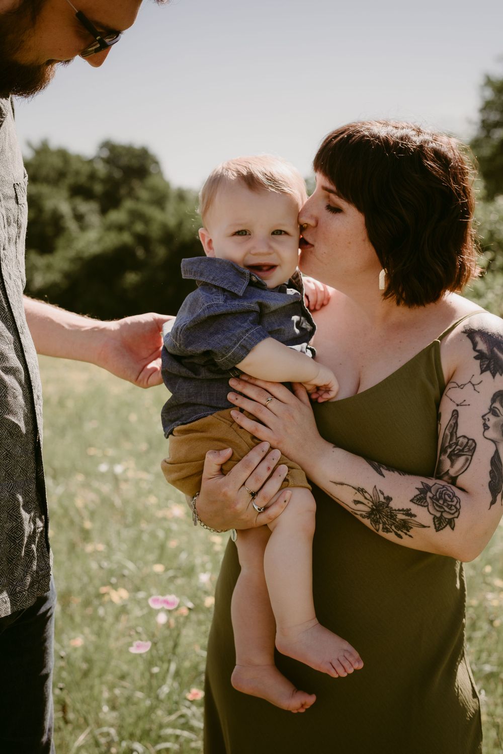 An intimate family moment captured in a wildflower field on a sunny afternoon.