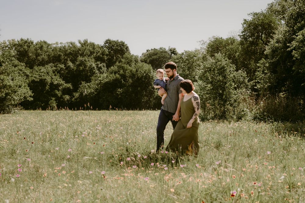 A couple strolls through a wildflower-filled meadow during golden hour.