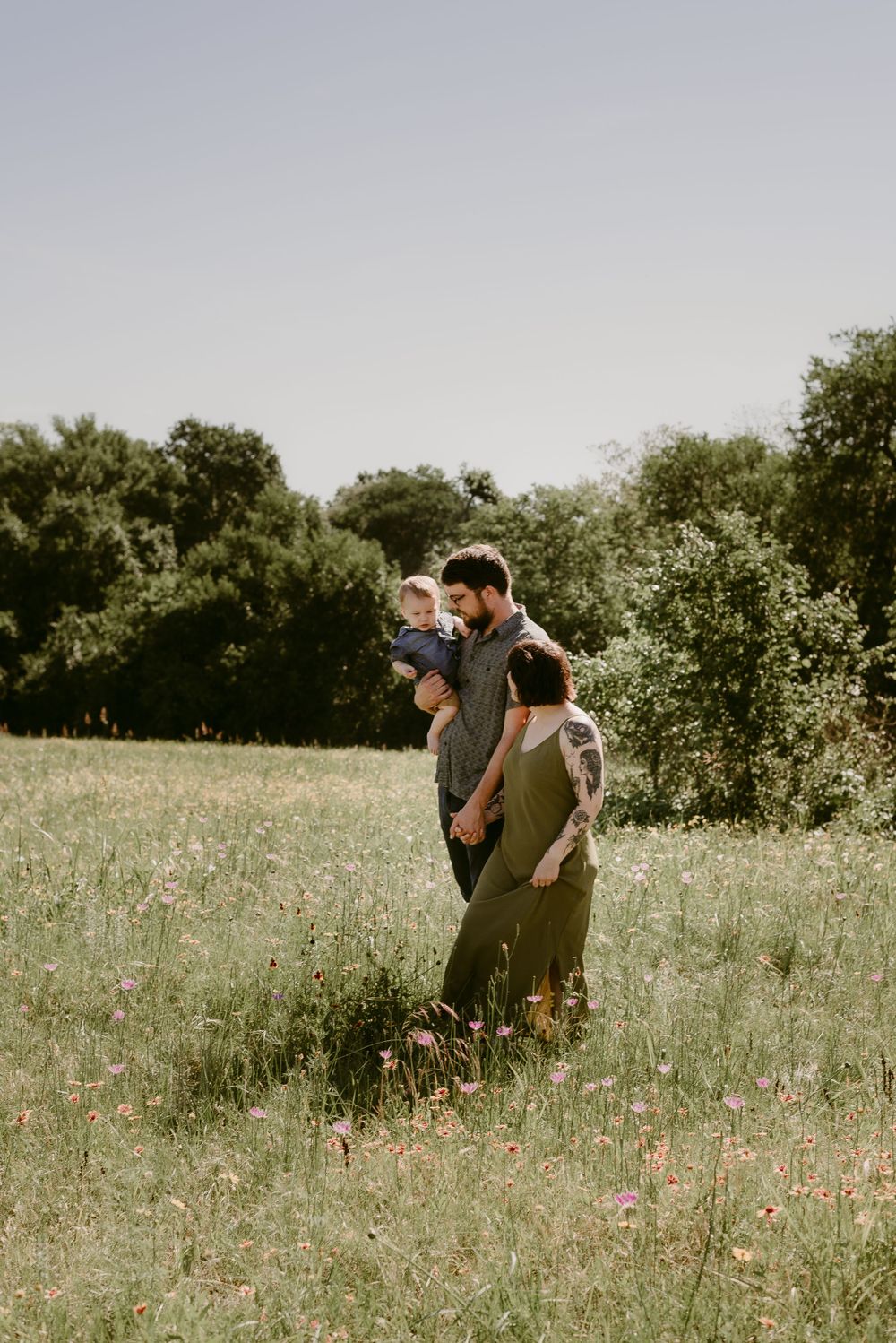 A family enjoying a peaceful moment together in a sun-drenched field of wildflowers.
