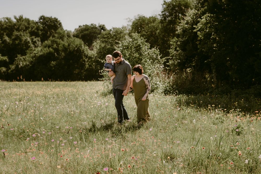 A family walking through a serene meadow on a sunny afternoon.