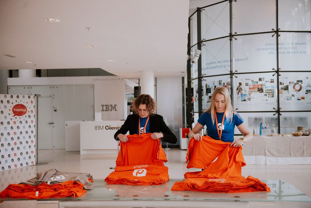 Two people folding bright orange t-shirts at an IBM branded workspace.