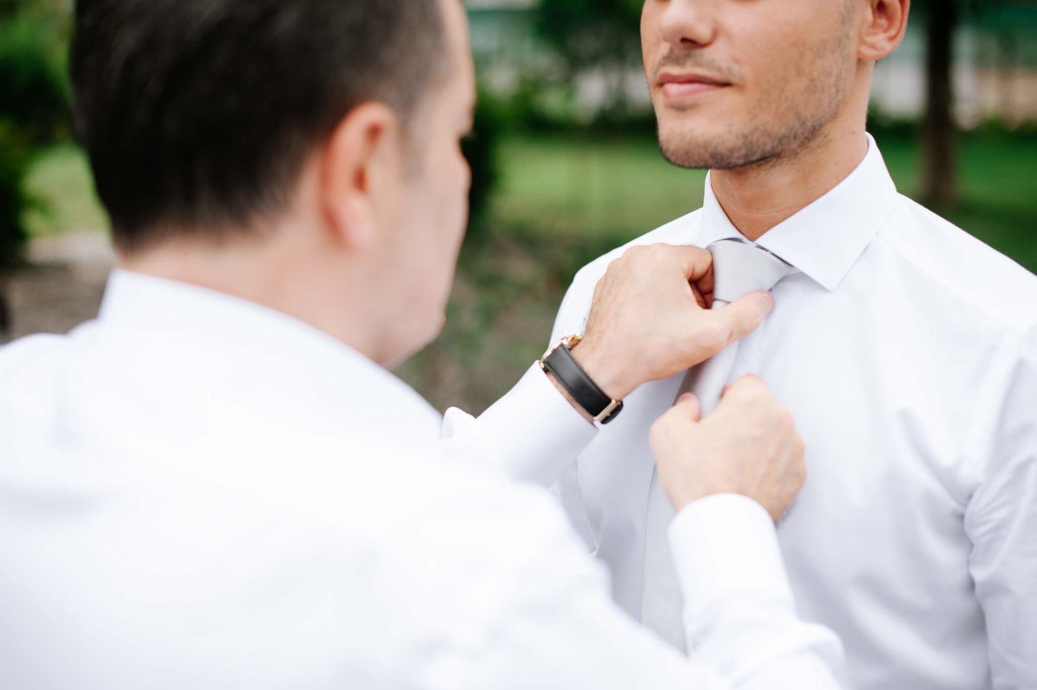 Someone adjusting a white tie on a formal shirt.