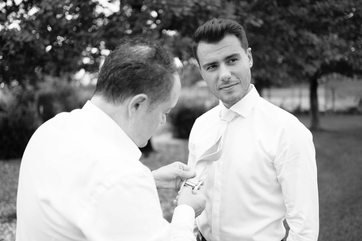 Two people in white shirts during a formal preparation moment.