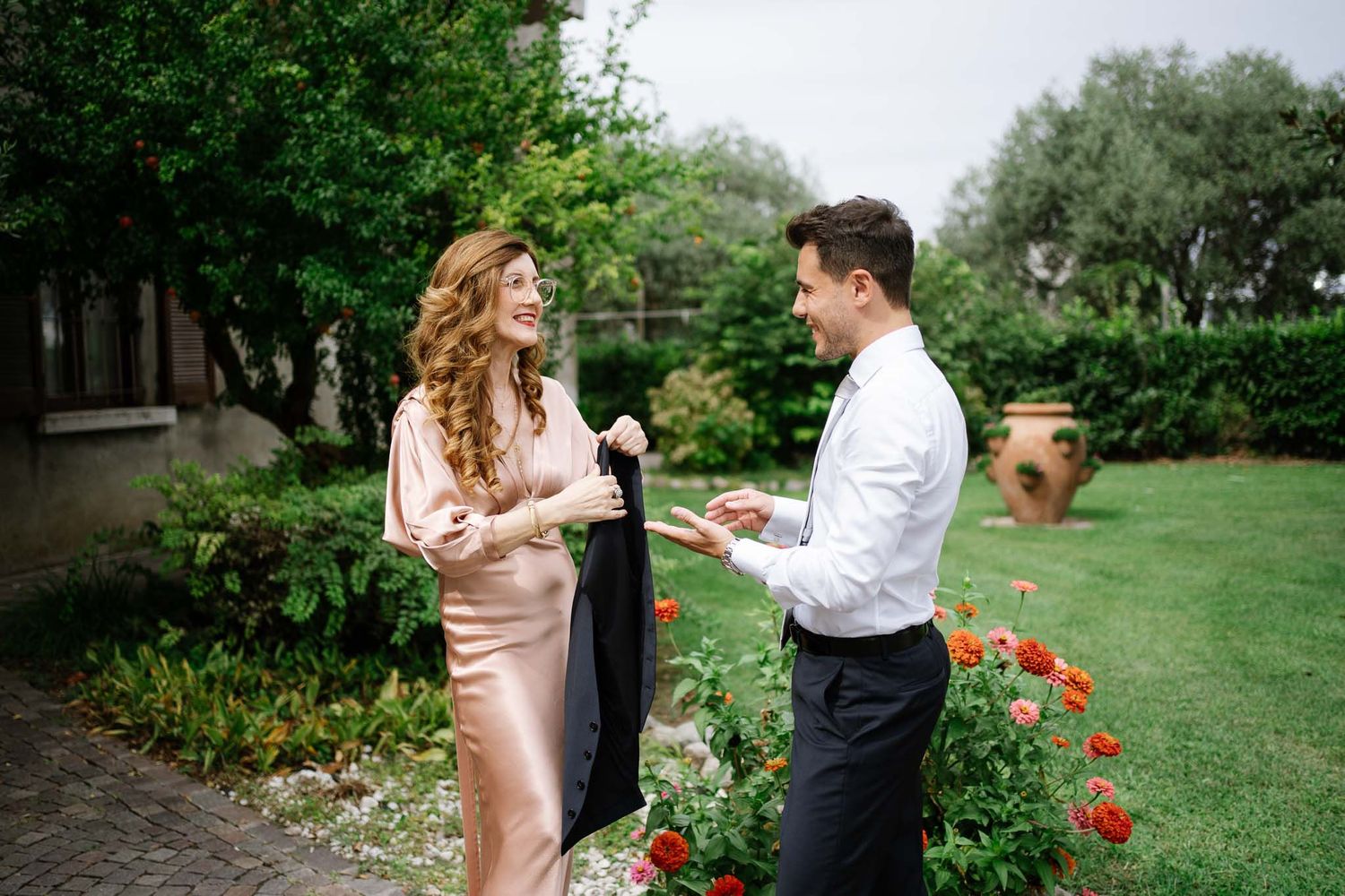 A stylish couple sharing a special moment in a lush garden with blooming flowers.