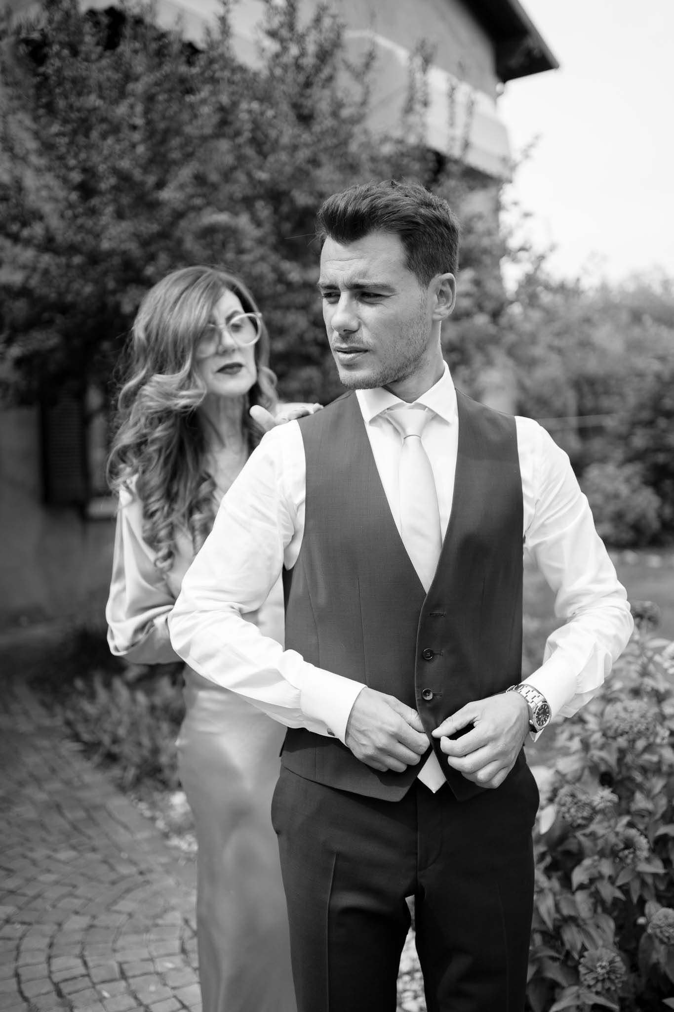 An intimate black and white portrait showcasing formal attire in a garden setting.