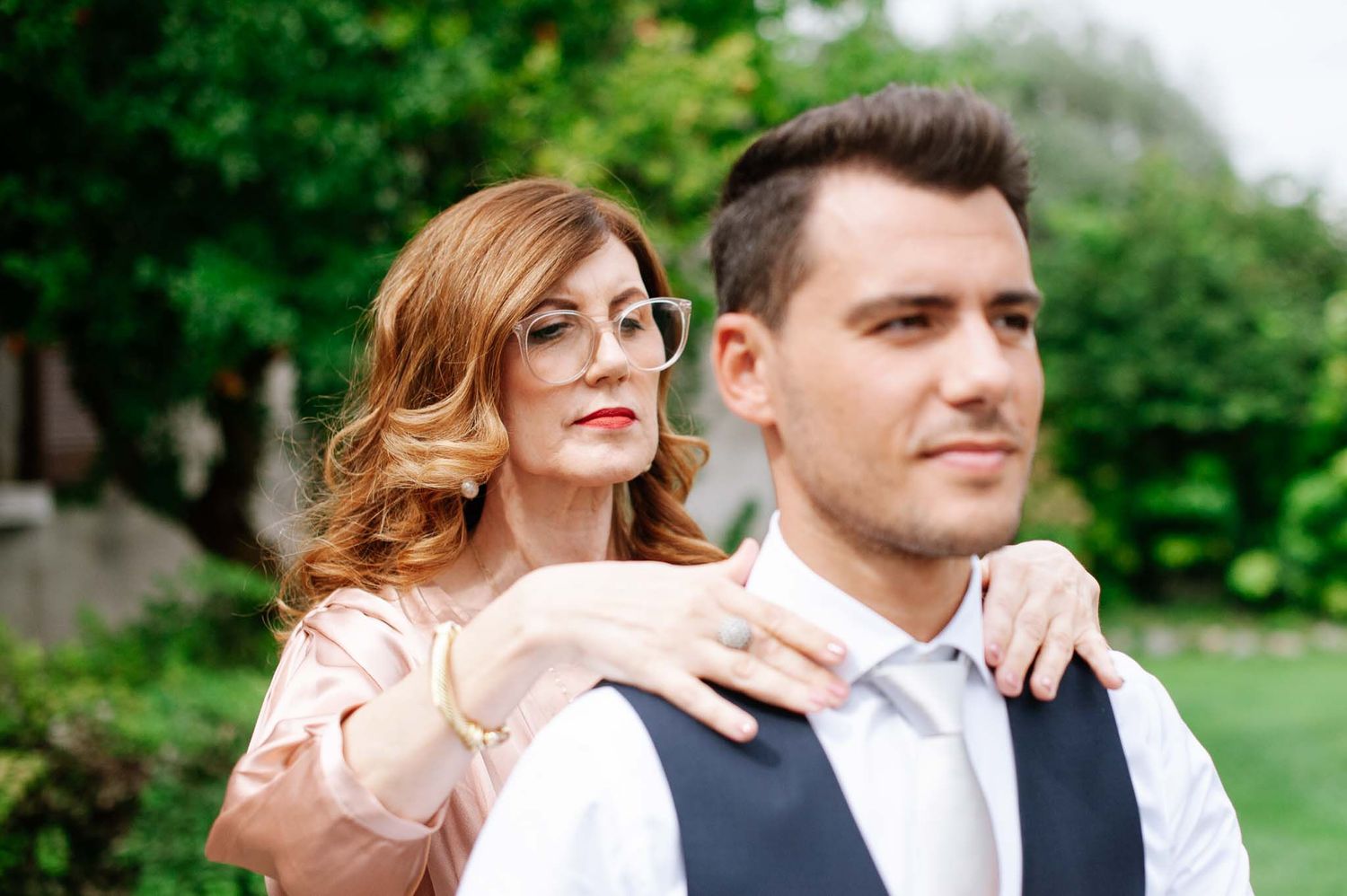 A tender moment captured between a couple in formal attire in a garden setting.