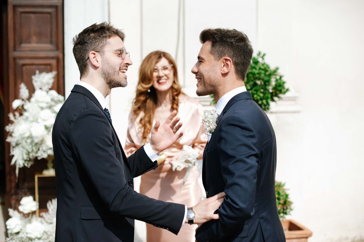 Two grooms share an emotional moment during a wedding ceremony.