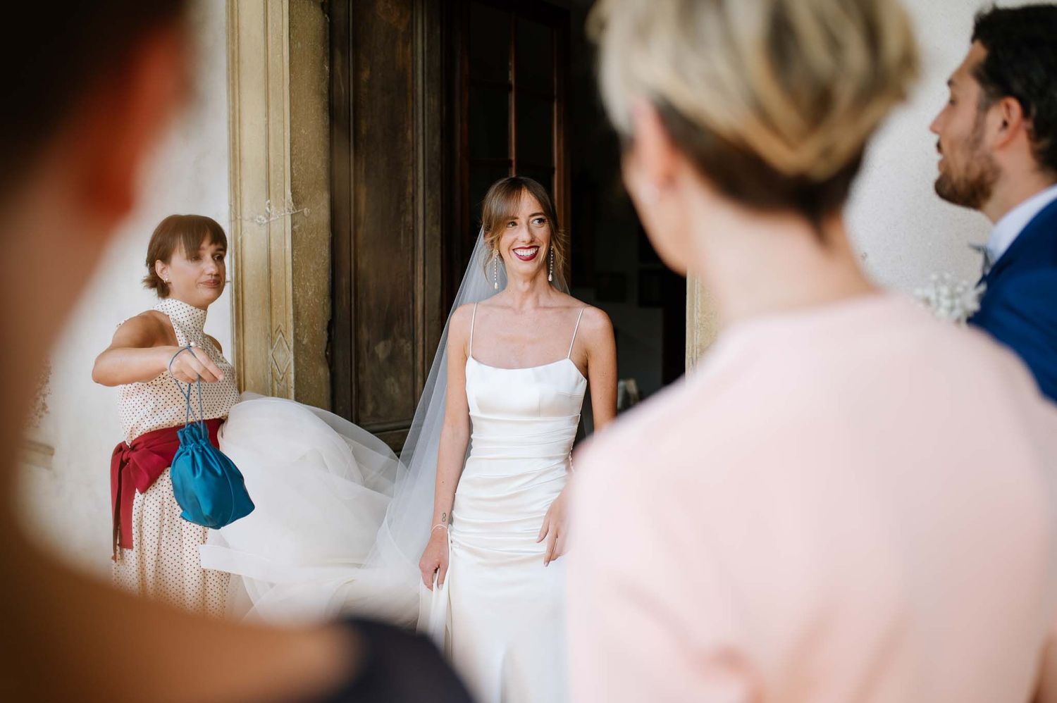 A bride in a white strapless gown walks through an elegant doorway at her wedding.