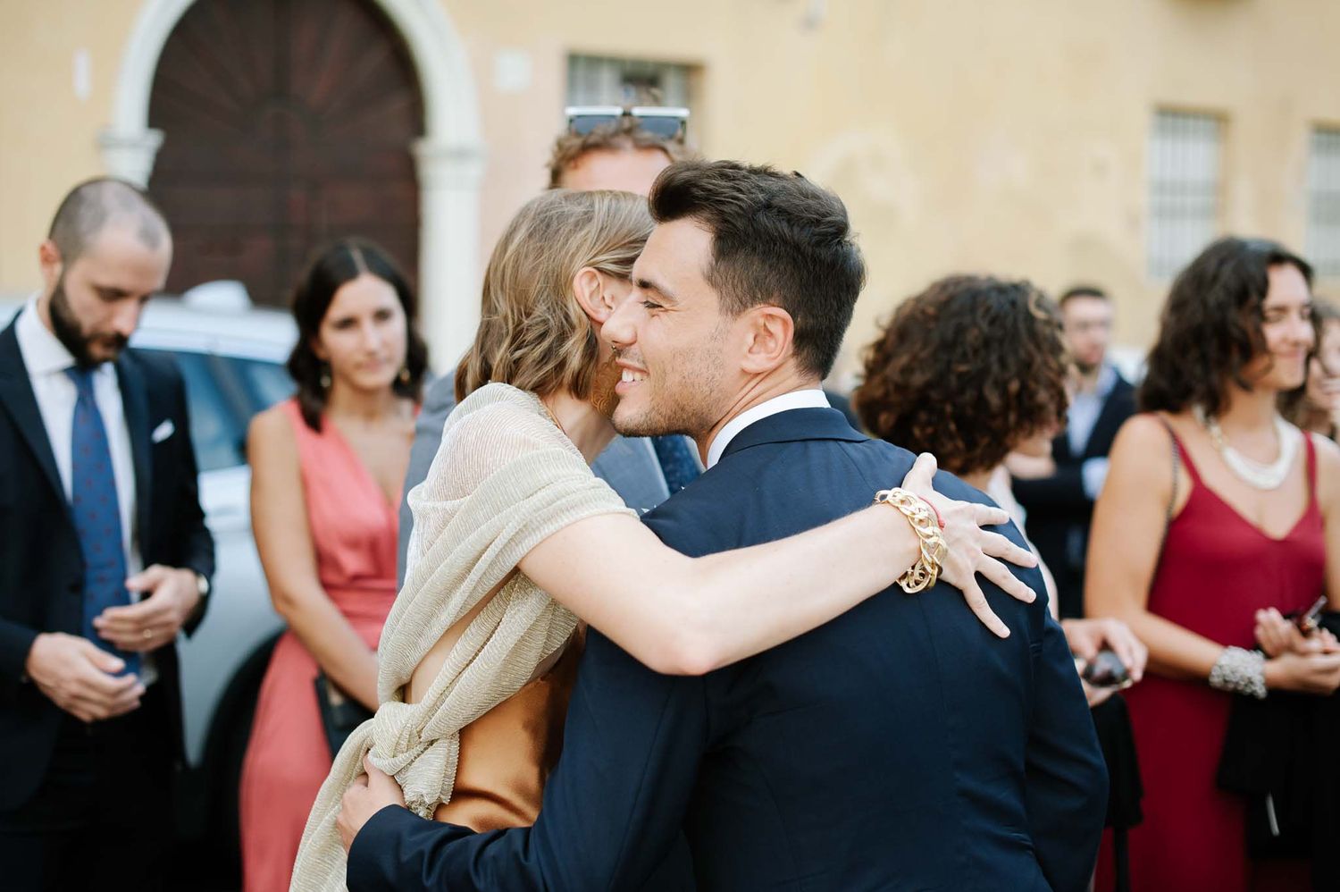 Wedding guests embrace and celebrate during outdoor reception festivities.