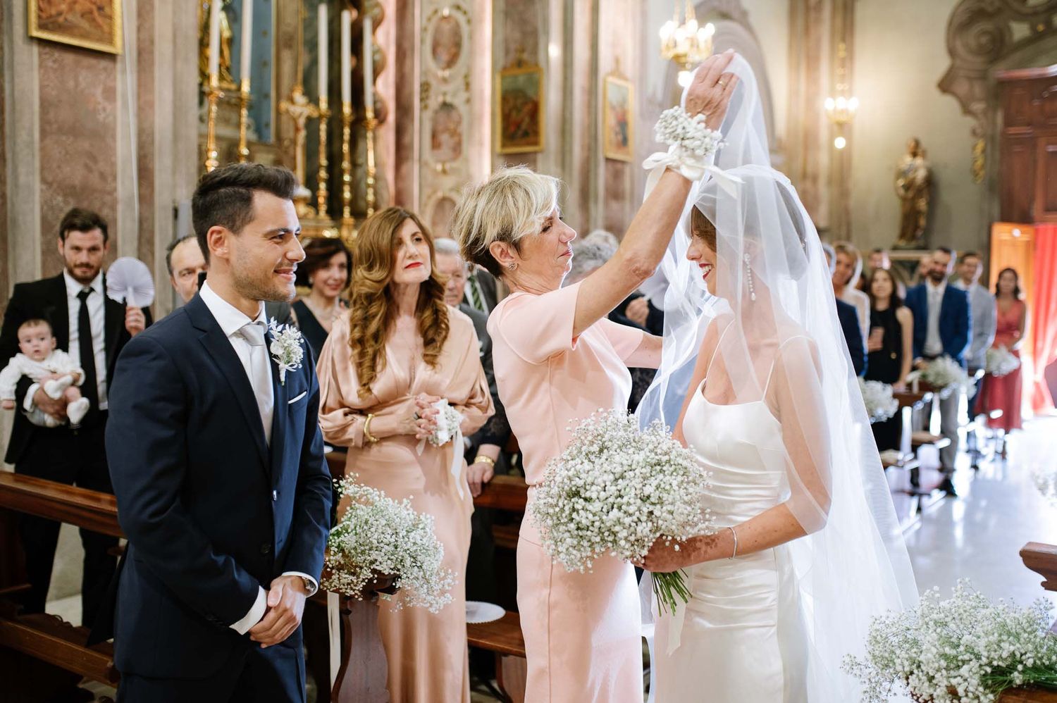 A joyful wedding moment captured in an ornate church setting with baby's breath decorations.