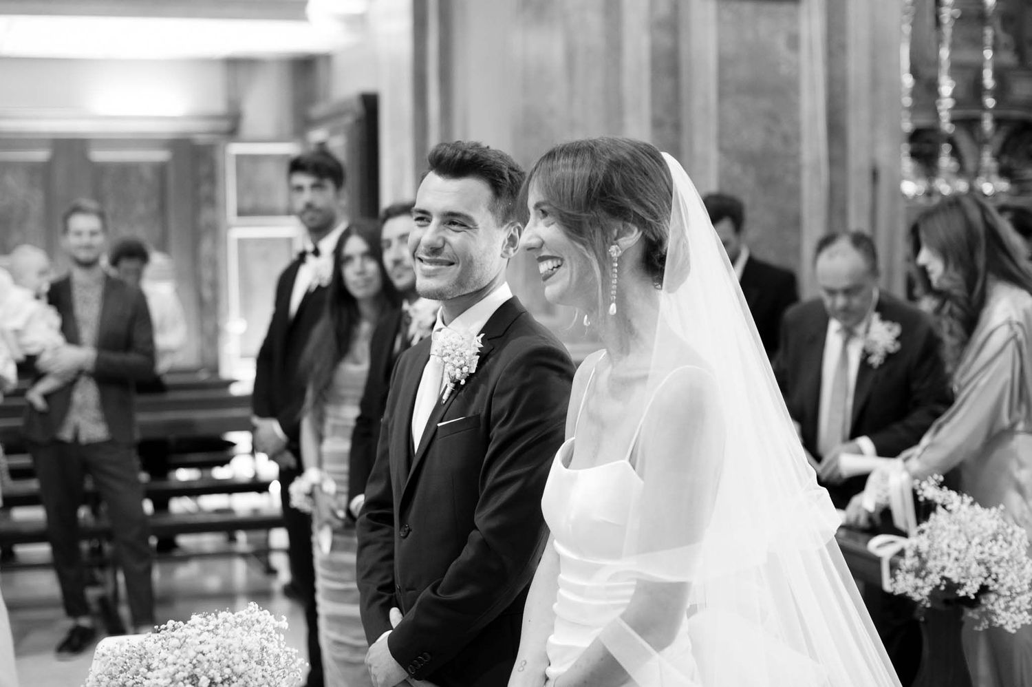 A joyful moment during a traditional church wedding ceremony with the couple standing at the altar in black and white.