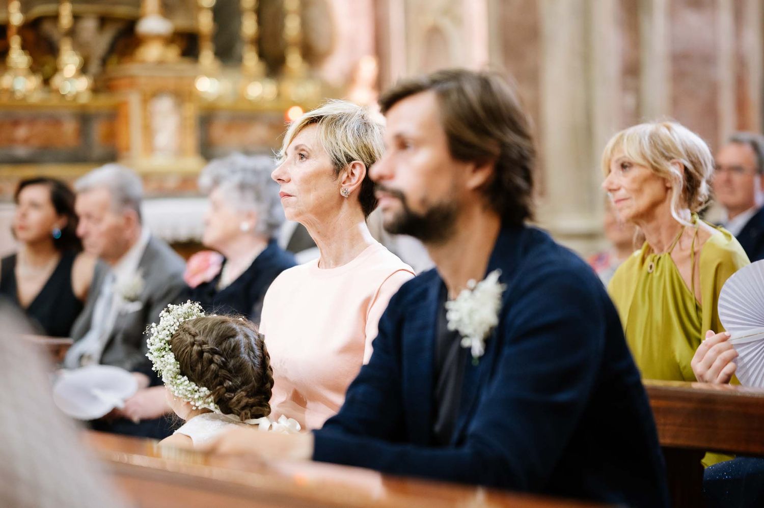 Wedding guests attentively watching ceremony in traditional church setting.