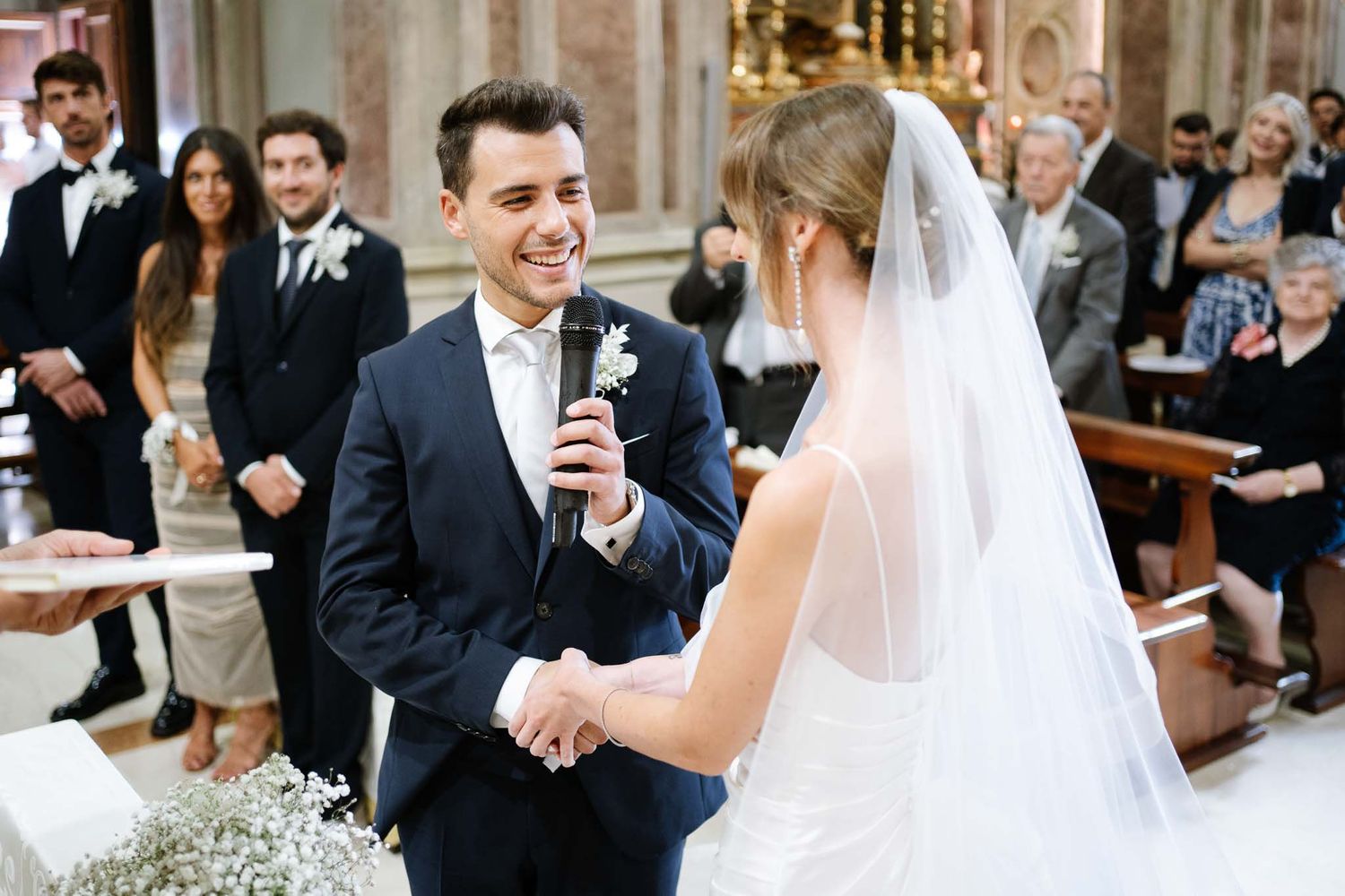 A couple exchanges vows during their wedding ceremony in a grand church setting.