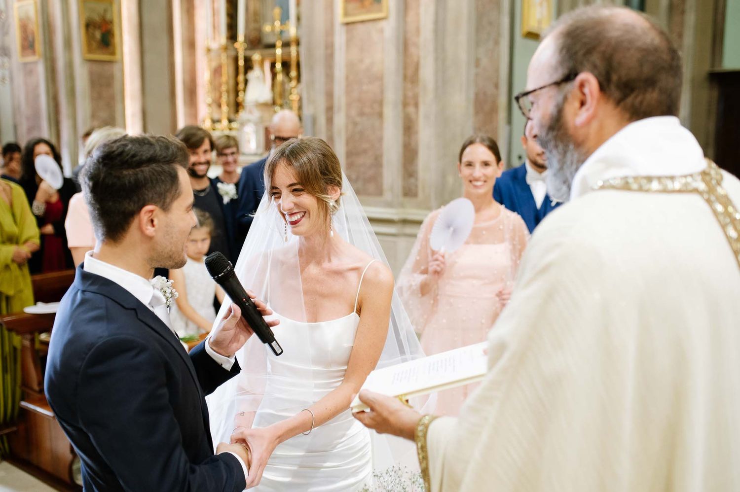 A wedding ceremony in progress inside a historic church with the priest officiating.
