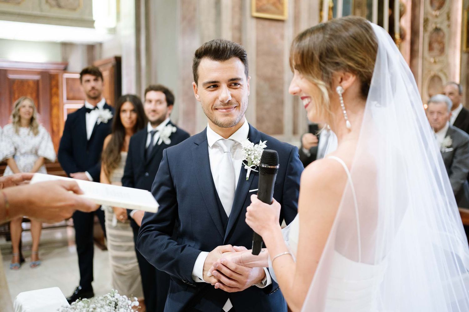 Couple exchanges rings during their wedding ceremony in a beautiful church setting.