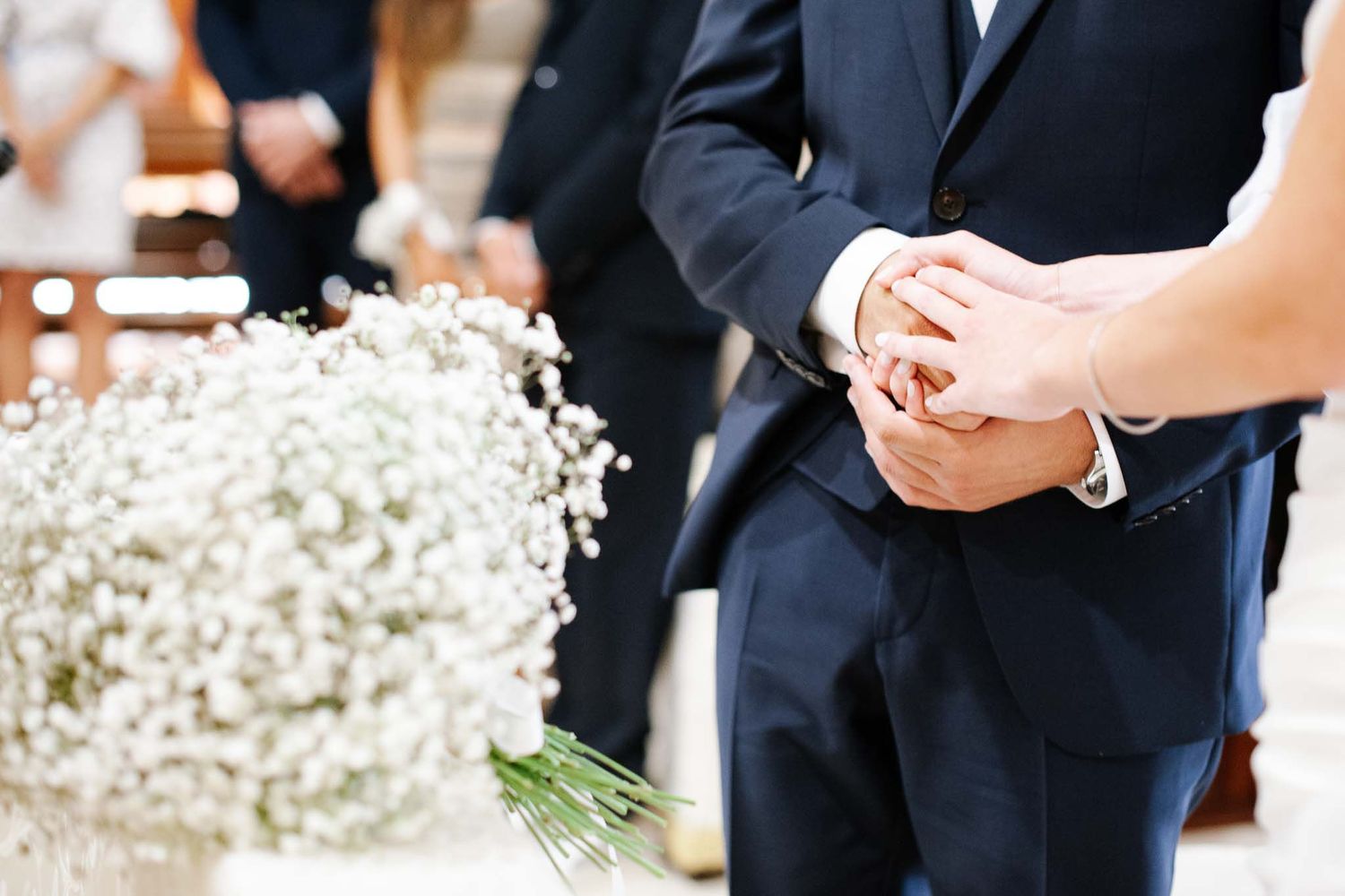 Close-up of hands exchanging rings with baby's breath flowers in the foreground.