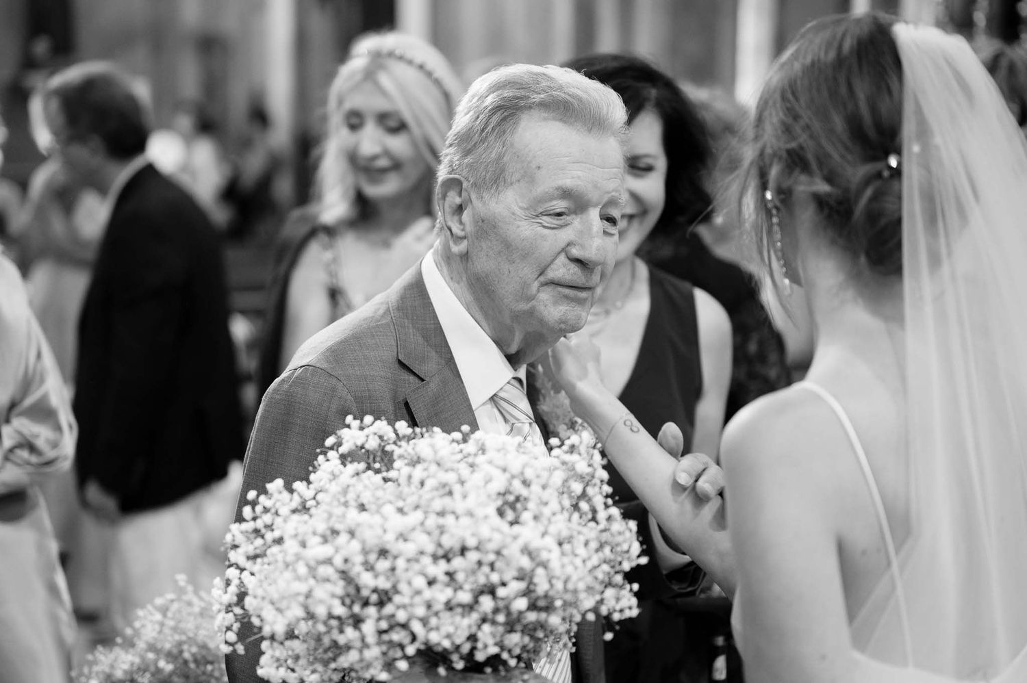 A black and white candid moment during wedding celebrations with baby's breath bouquet.