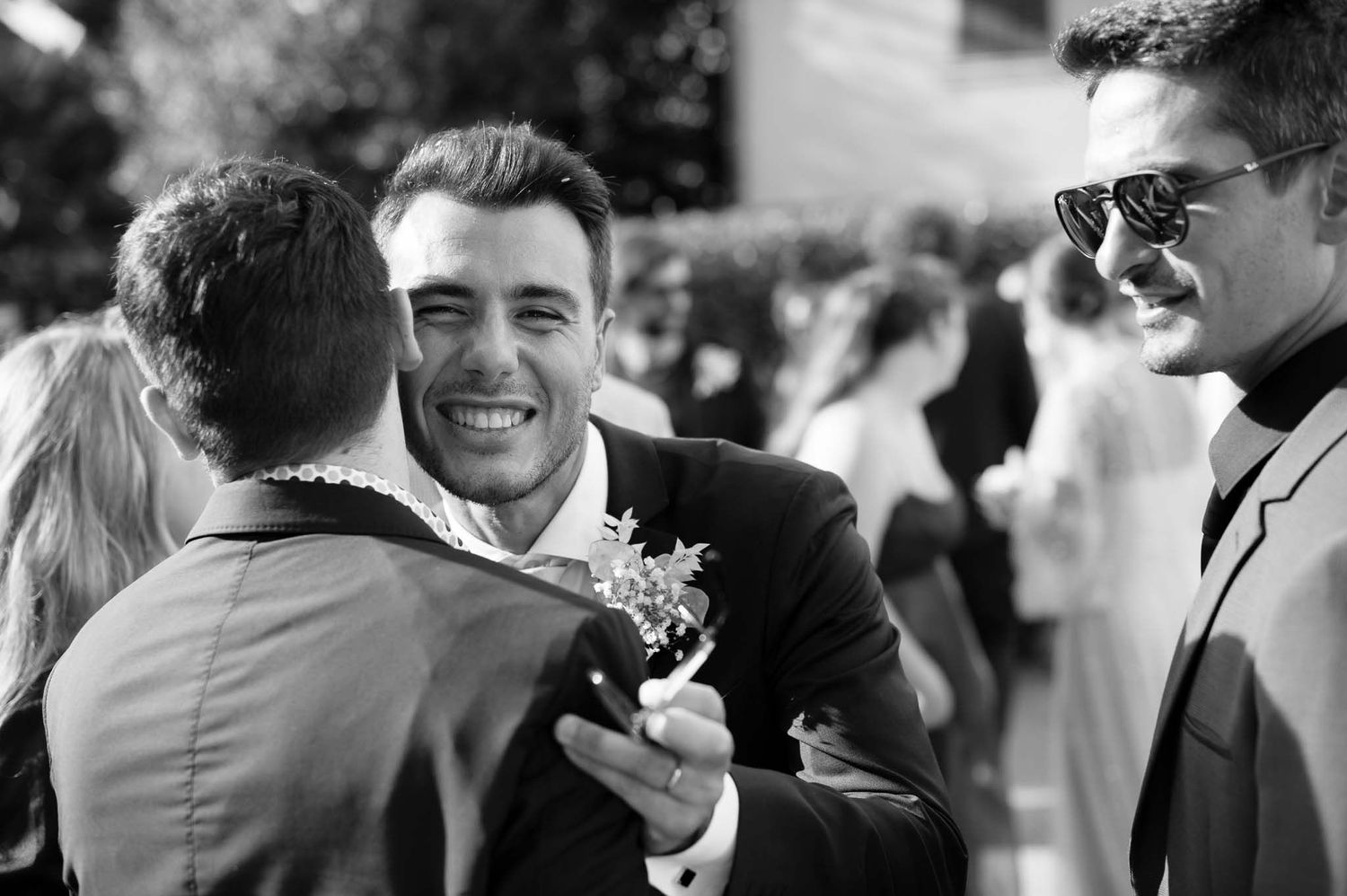 Wedding guests sharing laughs and embraces during outdoor reception.