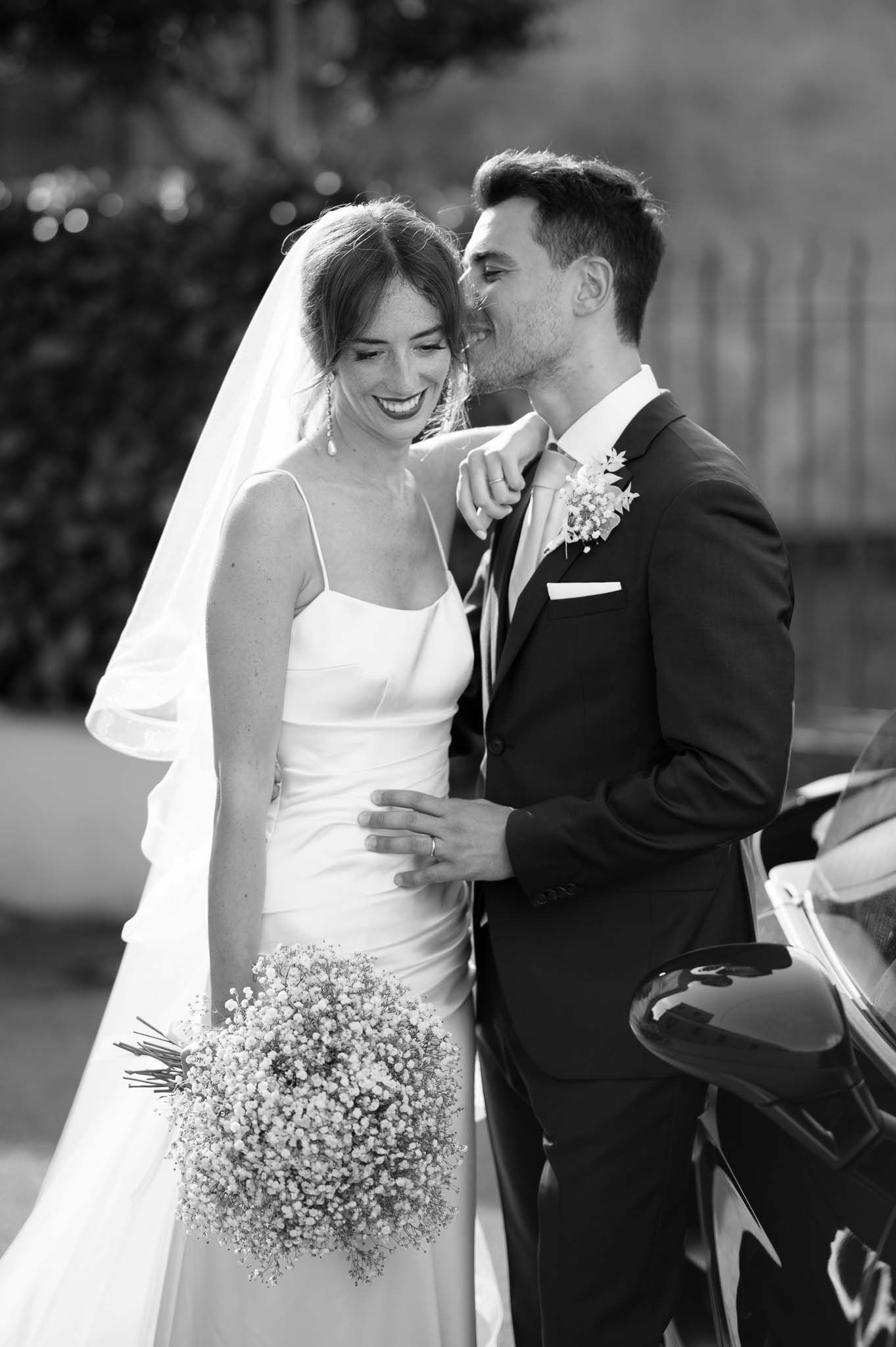 Wedding couple shares intimate moment with bride holding delicate baby's breath bouquet.