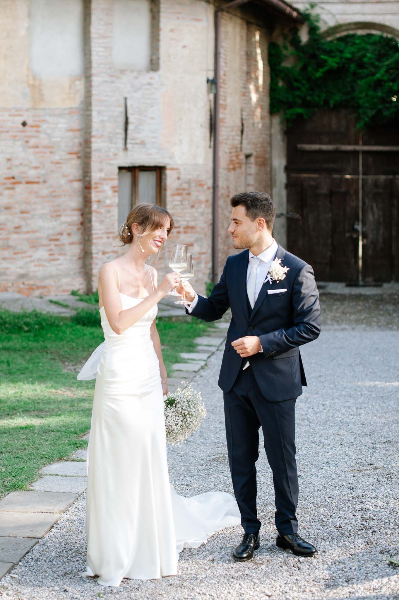 Wedding couple sharing celebratory toast outdoors at rustic venue.