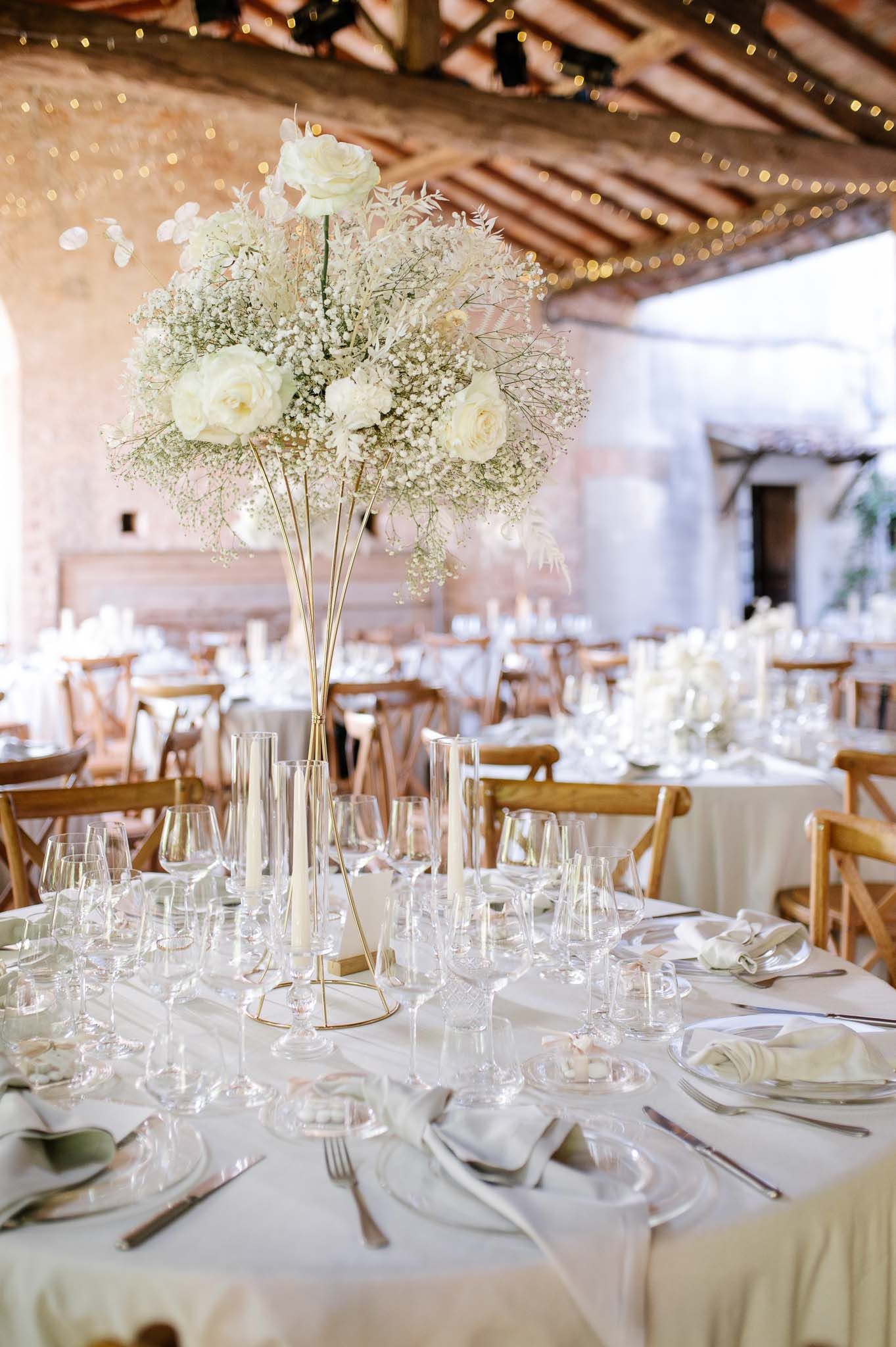 Elegant wedding reception table with tall baby's breath centerpiece and crystal glassware.