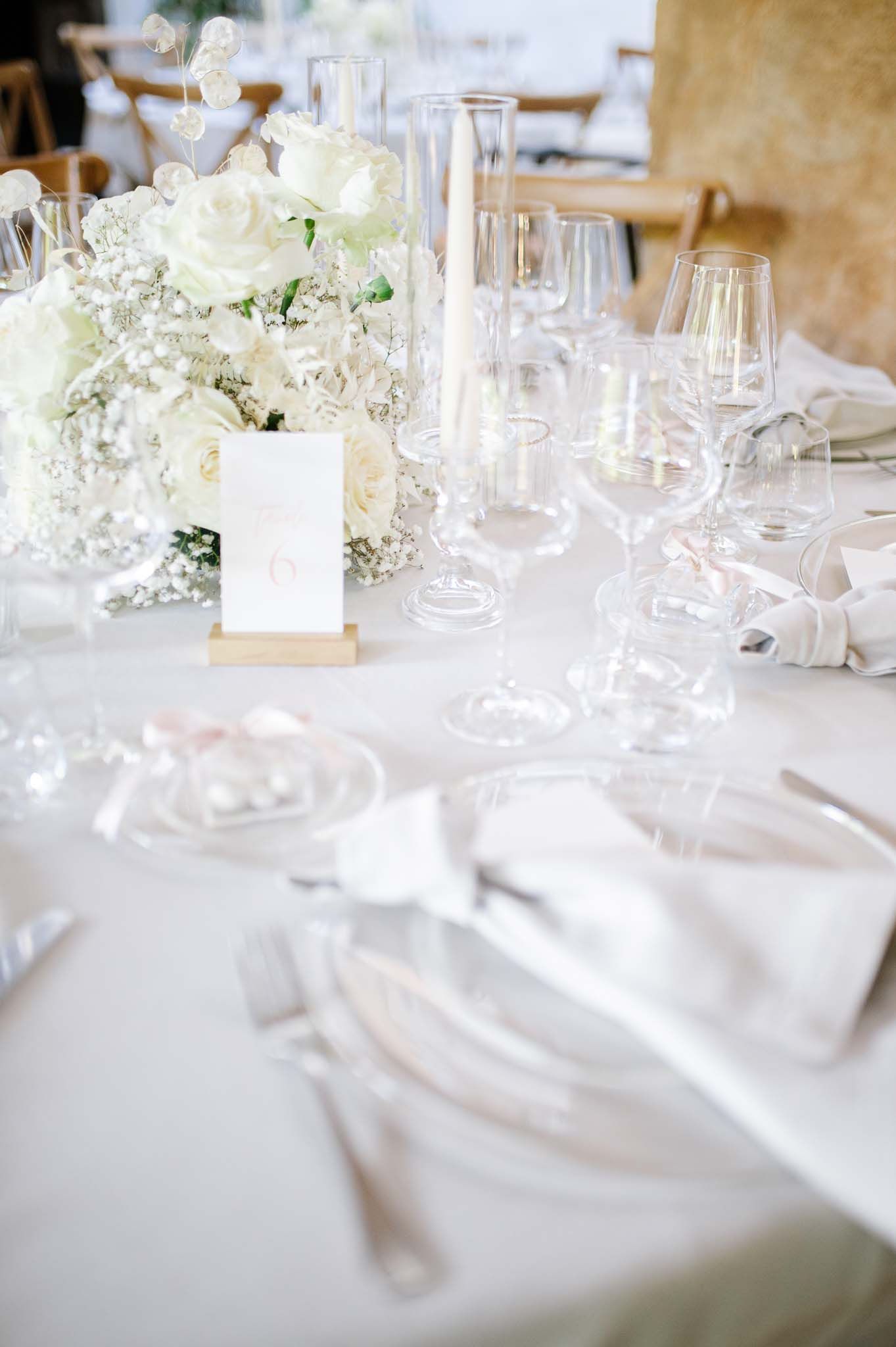 White wedding table decor with delicate floral arrangements and crystal stemware.