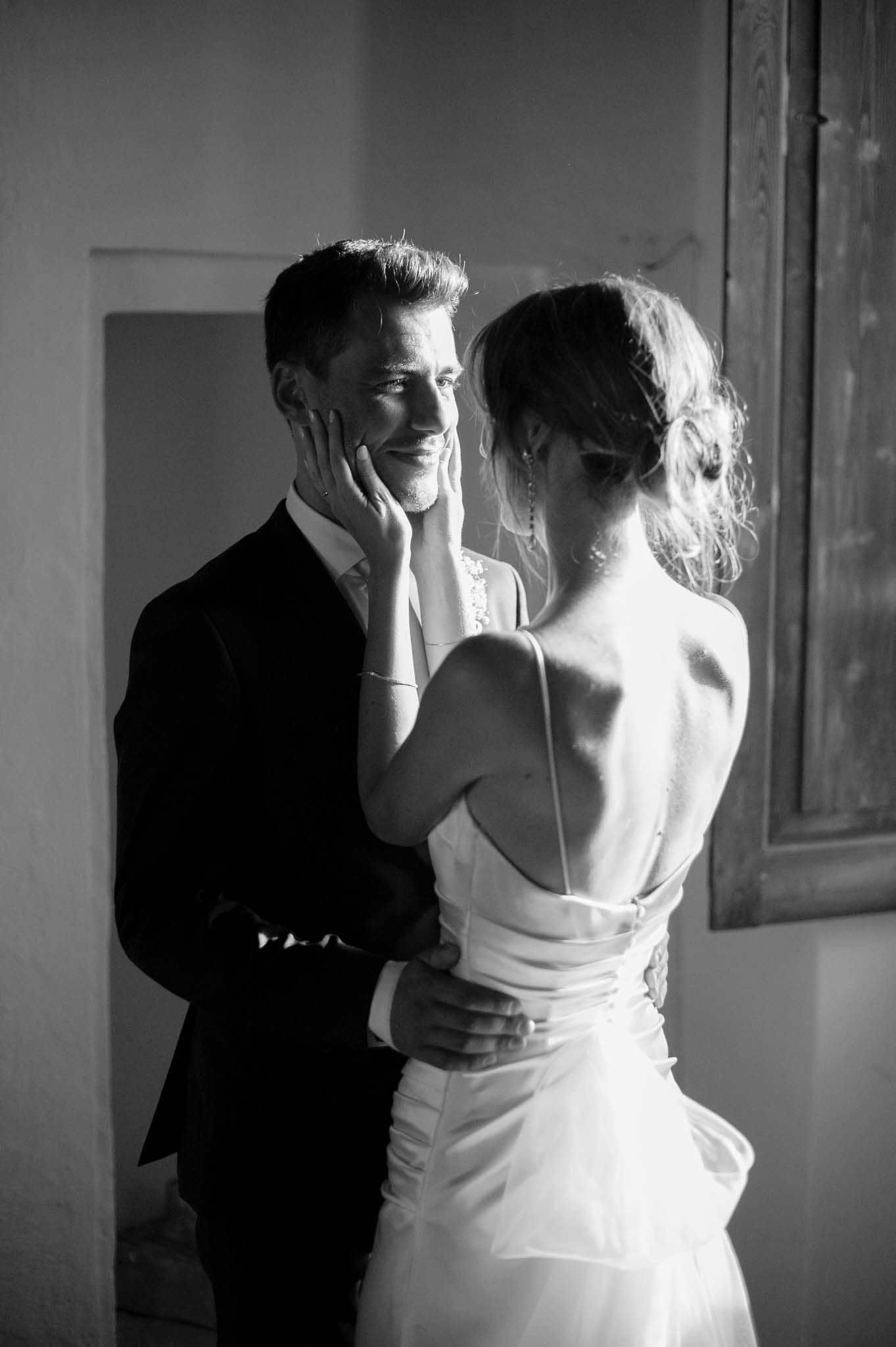 A black and white portrait of a couple in wedding attire sharing an emotional moment together.