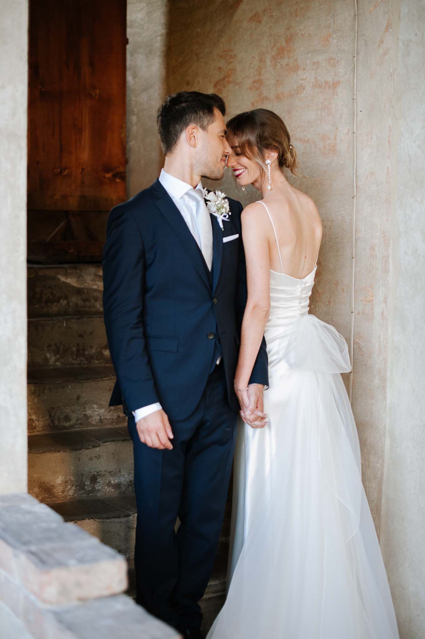 A romantic wedding couple share an intimate moment on historic stone steps.