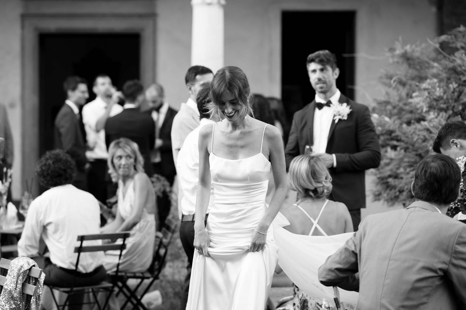 Black and white photo of wedding guests mingling during outdoor reception.